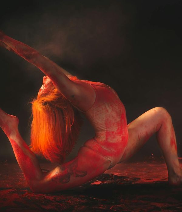 Woman in a dynamic yoga flow pose against a dark background.